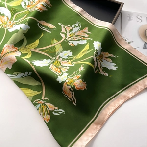Detail of green satin floral scarf with silk texture and contrasting pink hem edges