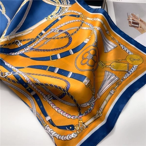 Detail of silk scarf with chain pattern, orange and navy blue color contrast and satin texture