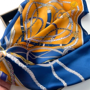 Close-up of luxury satin scarf with equestrian chain patterns in vibrant blue and orange