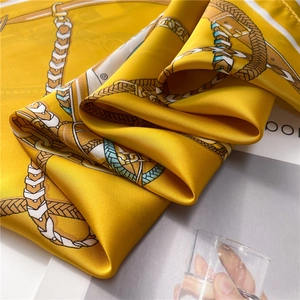 Detail of yellow satin scarf with elegant chain and buckle pattern in a soft texture