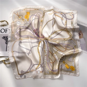 Detailed view of silk square scarf featuring gold chain and equestrian belt patterns