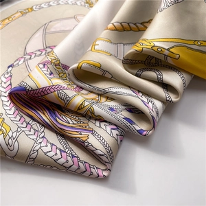 Detailed view of silk-like scarf with equestrian chain print and smooth satin texture