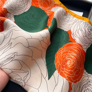 Detail of camellia floral silk scarf showing vibrant orange and green satin texture