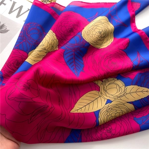 Detail of satin camellia scarf showing vibrant floral patterns and glossy silk texture