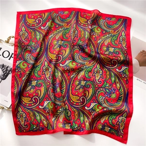 Pañuelo de seda rojo con estampado paisley y revista de moda sobre fondo blanco