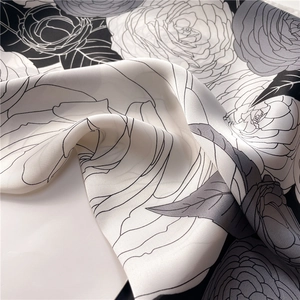 Close-up of silk-textured scarf with monochrome floral print and elegant satin sheen