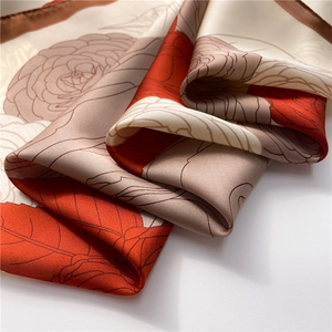 Macro detail of camellia floral print on a soft satin silk scarf with elegant rolled edges