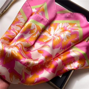 Vista detallada de un elegante pañuelo de seda con motivos florales abstractos rosa y naranja