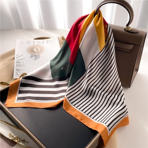 Fashion silk scarf with geometric stripes and vibrant color blocking tied on a handbag