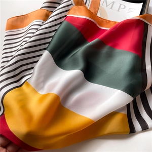 Detail of silk-like scarf with geometric stripes and vibrant multi-color patchwork patterns