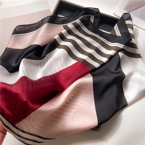 Detail of silk-like scarf with geometric stripes in red, black, and white colors