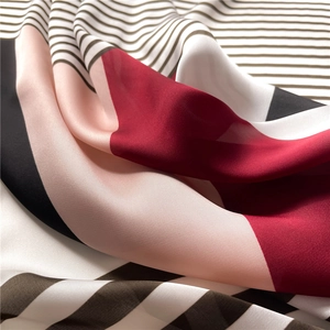 Macro view of geometric striped silk scarf showing smooth texture and elegant drape