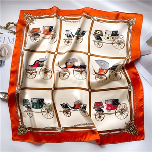Detalle de pañuelo de seda con estampado de carruajes vintage y bordes de color naranja