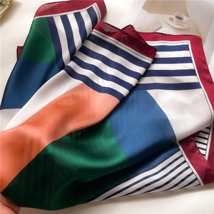 Detailed view of geometric striped silk scarf with elegant drape and satin texture