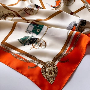Detalle de pañuelo de seda con estampado de carruaje naranja y cadenas de oro