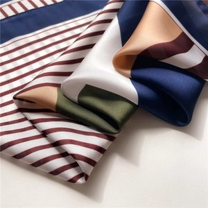Detail of silk-like scarf showing geometric stripes and soft textured fabric folds