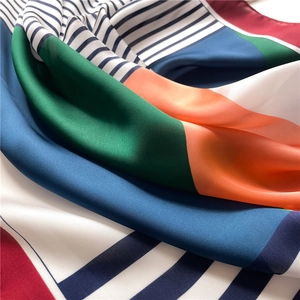 Detailed view of striped geometric silk scarf with navy blue and orange color block patterns