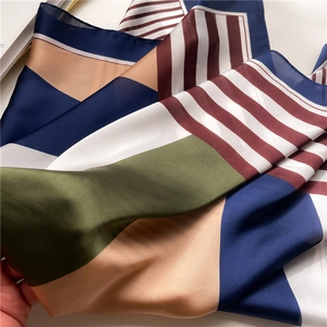 Detailed close-up of a satin scarf showing navy, green, and striped color-block textures