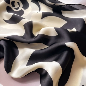 Detail of silk camellia square scarf showing premium glossy texture and neat hemmed edges