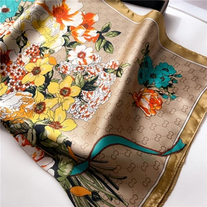 Detail of premium silk scarf featuring vibrant floral prints and golden monograms