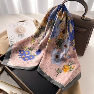 Floral silk scarf in pink and gray with satin texture draped elegantly on a handbag
