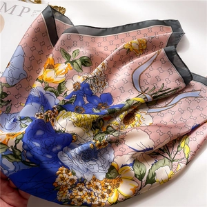 Detailed view of silk square scarf featuring interlocking logo and vibrant floral patterns