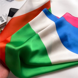 Detalle de un pañuelo de seda geométrico colorido con textura satinada y caída elegante