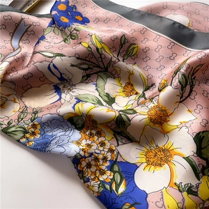 Detail of pink silk square scarf featuring floral prints and vintage logo patterns