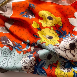 Close-up of silk texture scarf with orange floral prints and interlaced pattern