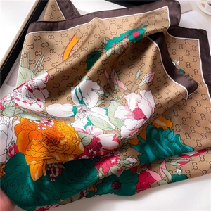 Detailed view of floral silk scarf featuring satin texture and orange blossom patterns