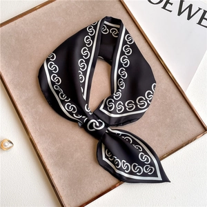 Detailed close-up of a long silk scarf with black satin and white geometric chain patterns