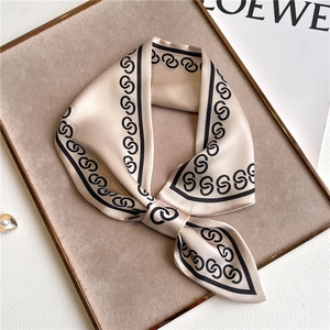 Elegant beige satin skinny scarf with chain pattern on a premium display tray