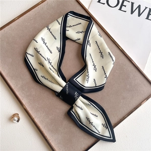 Detail of a tied ribbon scarf with navy borders and letter print on a display tray