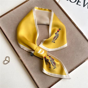 Detail of yellow silk twilly scarf with soldier print and white letter D logo