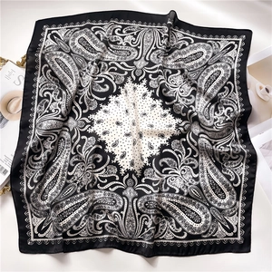 Detail shot of a black and white paisley silk scarf with elegant folds on a white background
