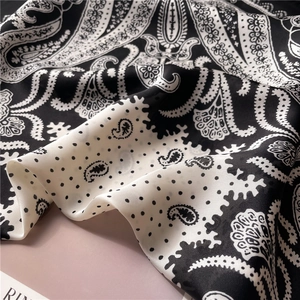 Macro detail of silky black and white paisley fabric with elegant draping folds