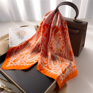 Orange paisley silk scarf draped on a handbag with elegant vintage pattern design