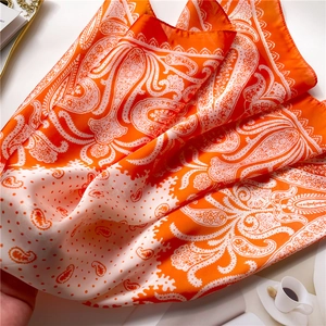Detail of bohemian orange paisley silk scarf with white polka dots on an elegant table
