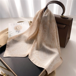 Detail of silk square scarf with paisley pattern draped over a luxury leather handbag