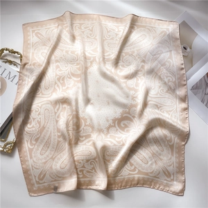 Detail shot of champagne gold paisley silk scarf with glossy texture and fine stitching
