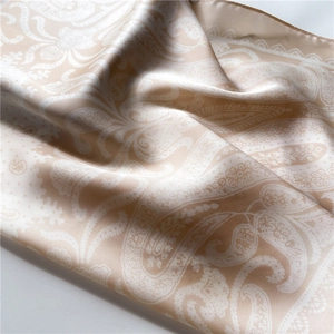 Macro shot of paisley pattern silk scarf with elegant champagne and white silky texture