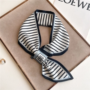 Classic black and white striped satin skinny scarf displayed on a minimalist beige board