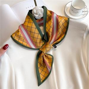 Detail of yellow silk scarf with geometric dot patterns and a white camellia accessory