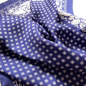 Macro shot of navy blue silk scarf with white geometric squares and floral patterns