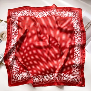 Detail of red silk-like square scarf featuring white rose patterns and vintage grid textures