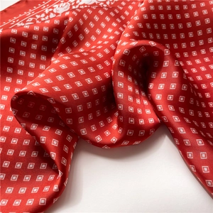 Macro detail of red silk scarf showing satin luster and white floral pattern borders