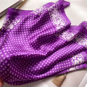 Detailed close-up of purple silk scarf with white floral patterns and soft drape