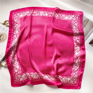 Detail of rose pink silk scarf showing elegant floral prints and geometric checkered patterns