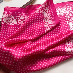 Close-up of silk scarf with rose print and geometric texture in vibrant magenta