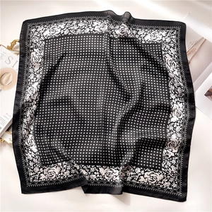 Close-up of silk-like square scarf featuring black and white rose patterns and polka dots
